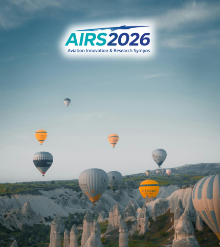 The unique landscape of Cappadocia with fairy chimneys in warm ochre and orange tones. The sky is blue and filled with colorful hot air balloons. In the sky, a sleek drone represent 'Innovation' for 'AIRS 2026' sypmposium and 'Cappadocia'.